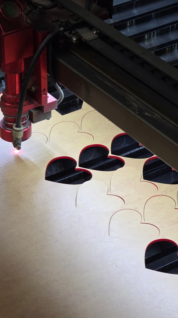 Laser cutter cutting heart shapes from a sheet of card for craft projects