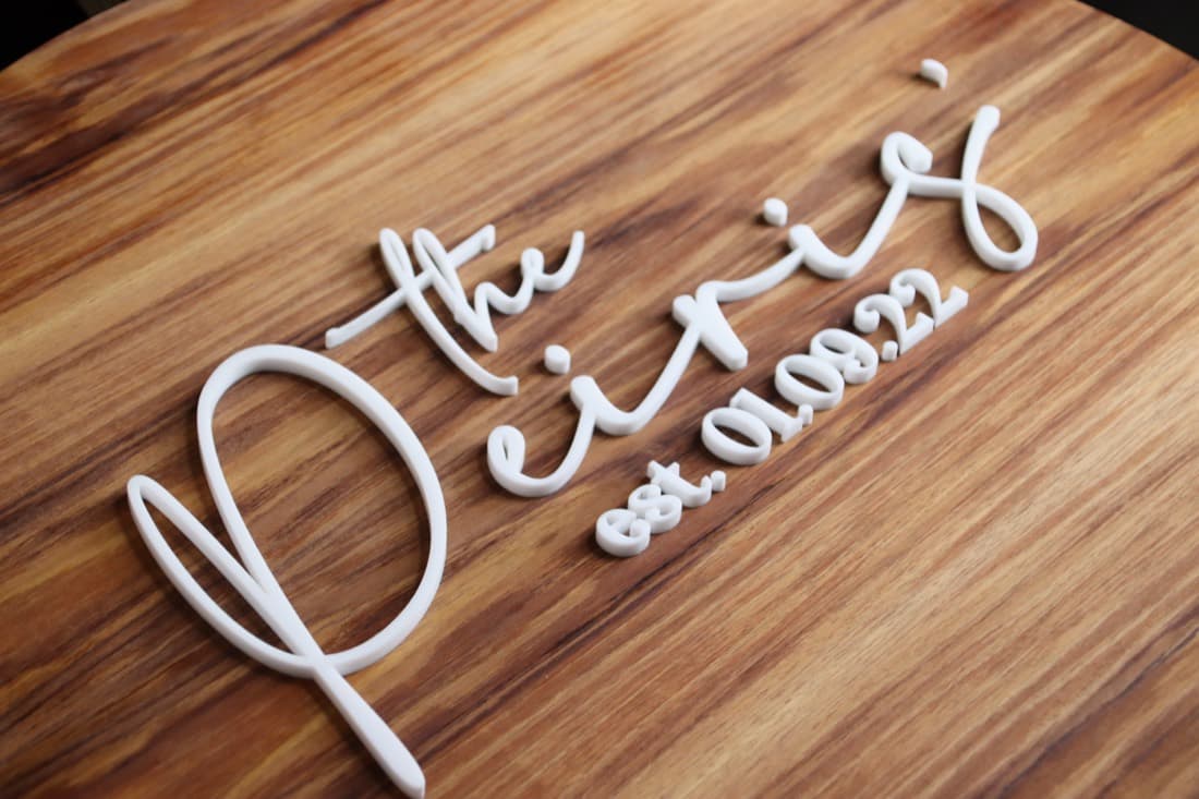 Raised white acrylic 'the Pirie' event signage mounted on a timber board