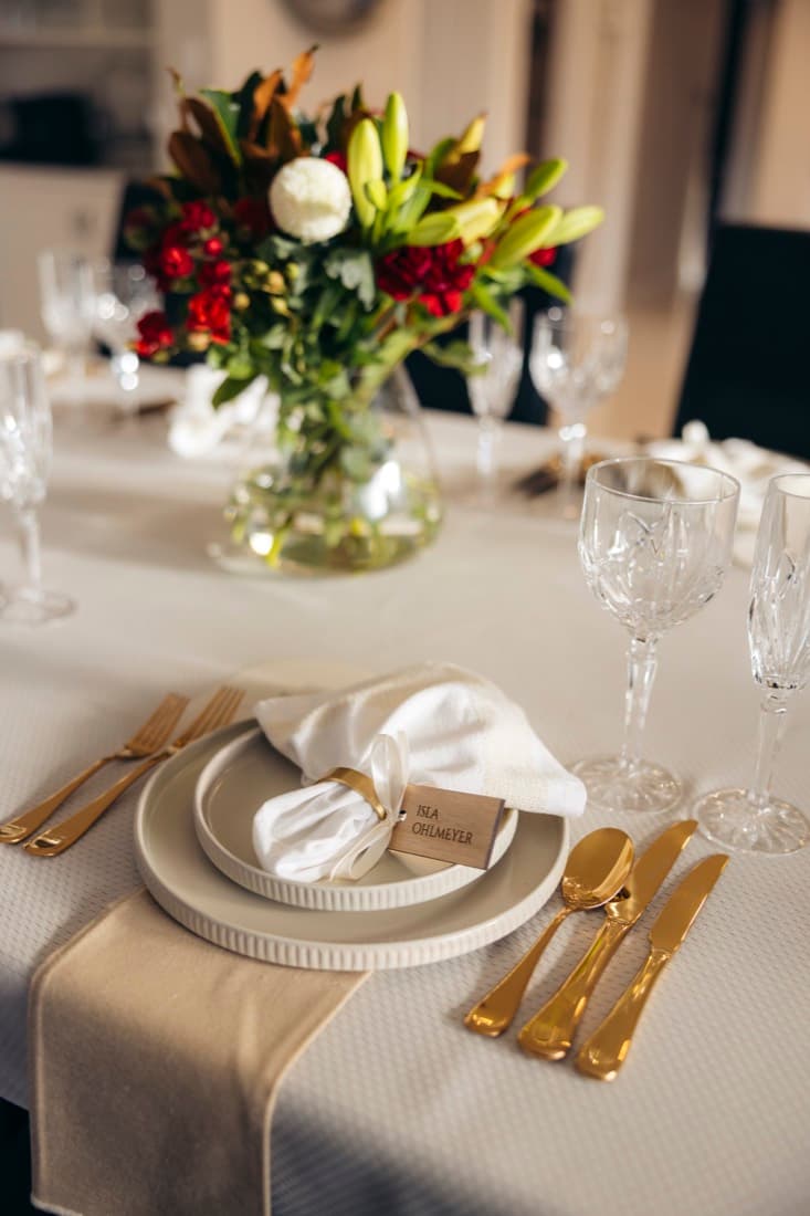 Elegant event table setting with floral centrepiece, gold cutlery and a name place card