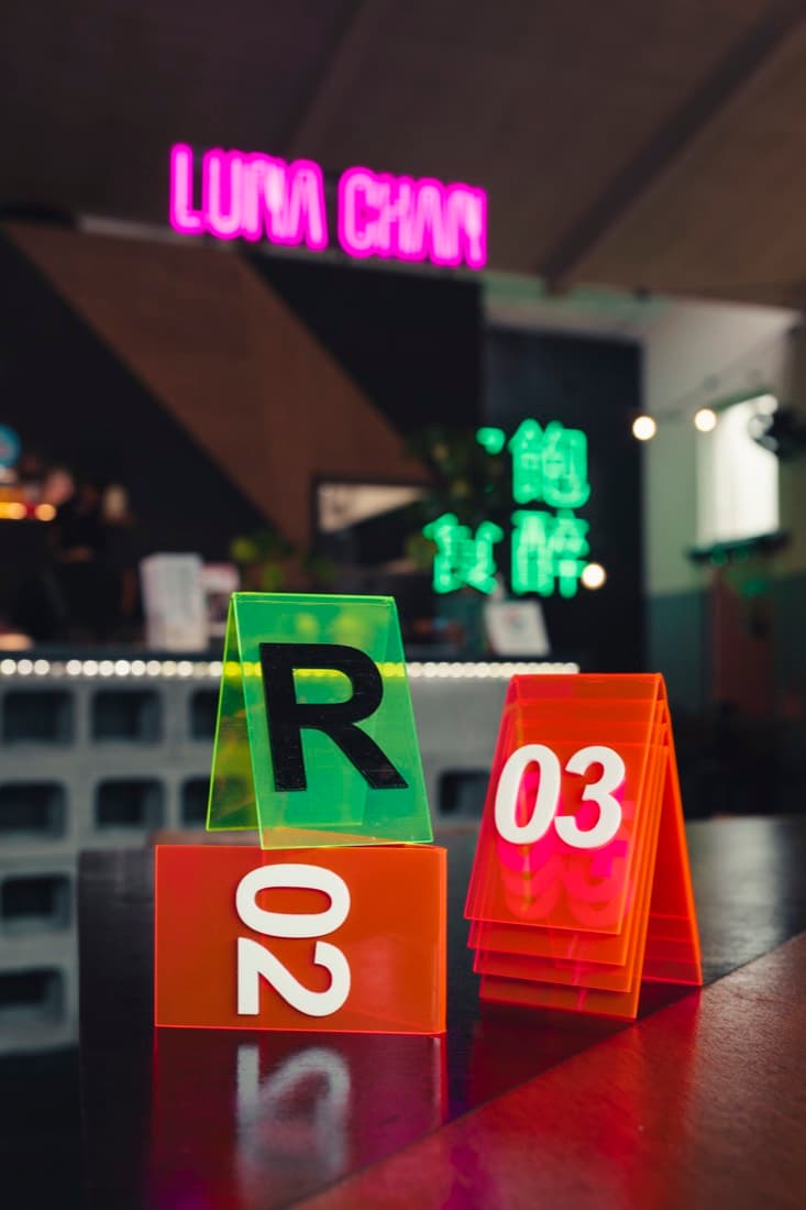 Neon-edged acrylic table number signs on a cafe counter