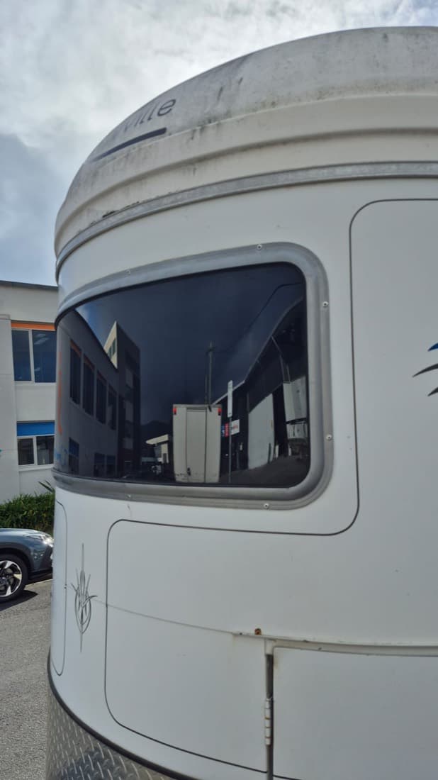 Close-up of a custom-fabricated tinted acrylic window replacement fitted into a motorhome body panel
