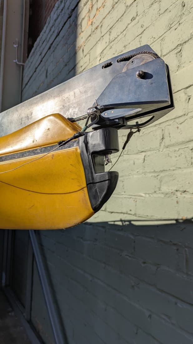 Kayak supported on a custom plastic-and-metal mounting cradle against a brick wall