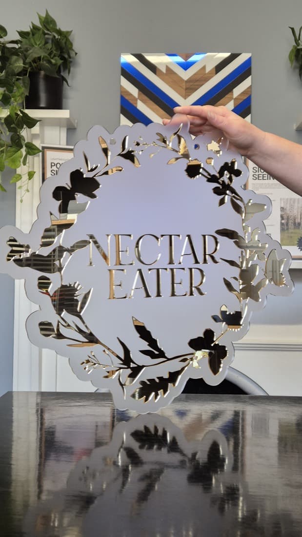 Mirror-gold acrylic 'Nectar Eater' market stall sign with laser-cut floral wreath detail