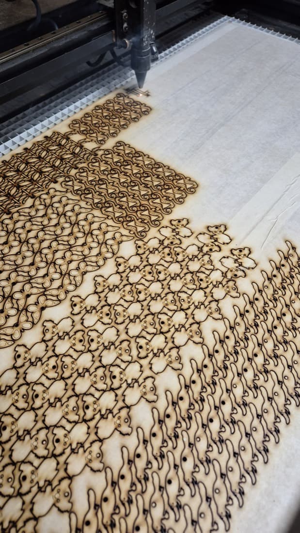 Laser cutting machine cutting intricate koala-shaped timber craft pieces from a sheet