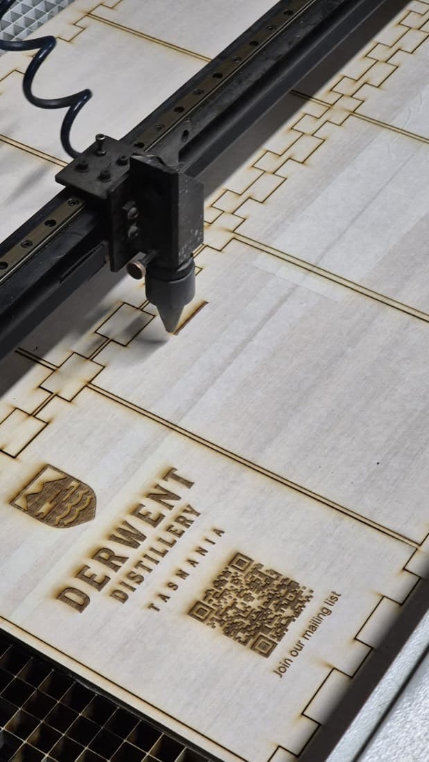 Close-up of a laser cutter producing decorative repeat-pattern timber shapes for market products