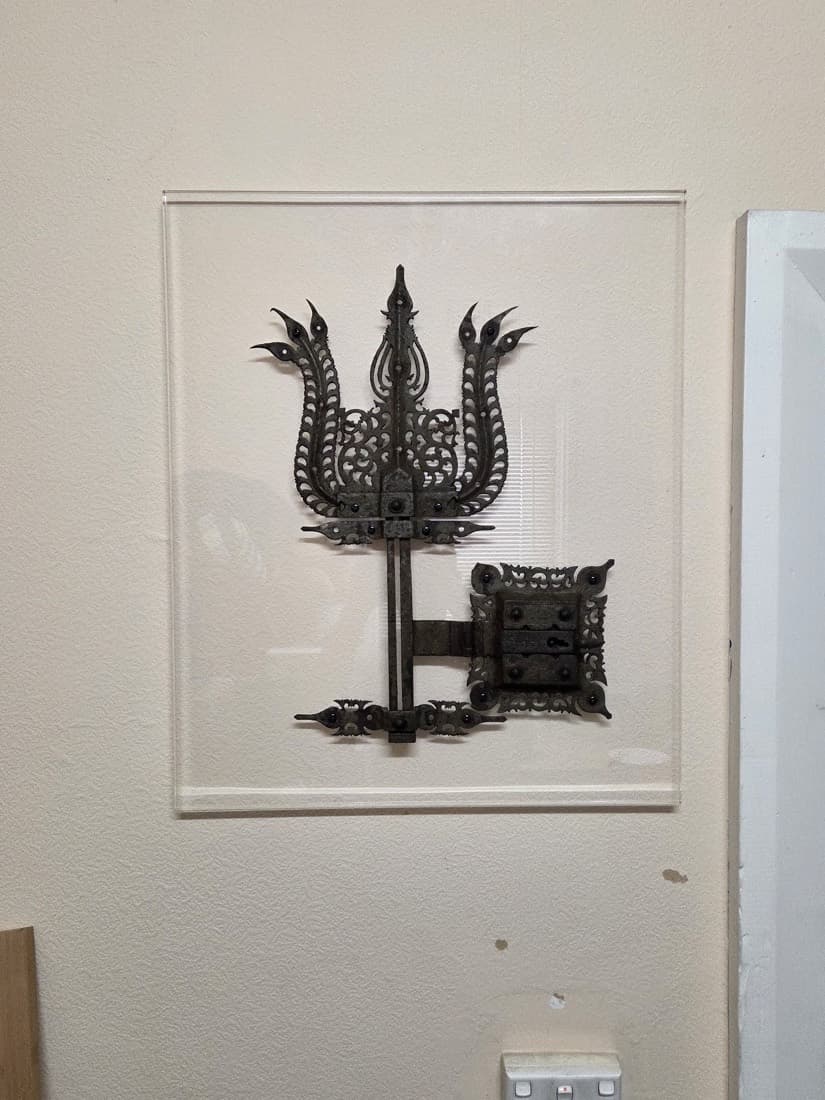 Antique wrought-iron artefact float-mounted between clear acrylic panels and hung on a gallery wall