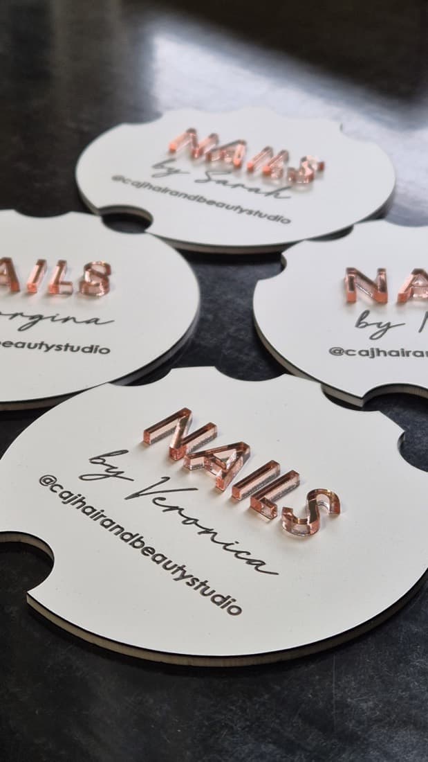 Laser-cut acrylic NAILS retail name badges in rose gold mirror finish
