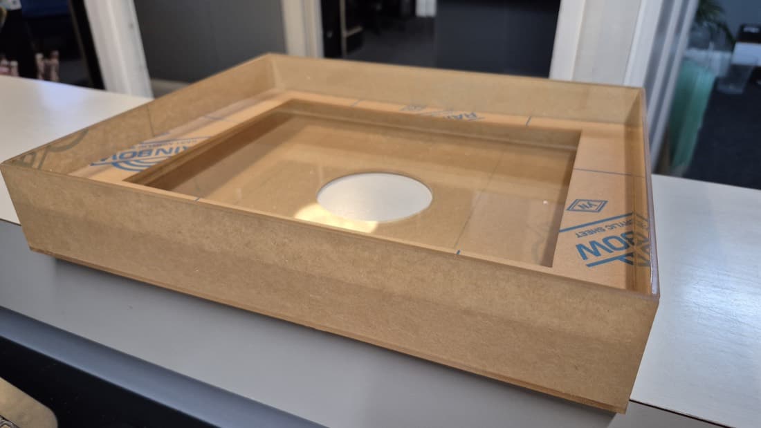 Acrylic and MDF display case cover with a circular cutout, angled view