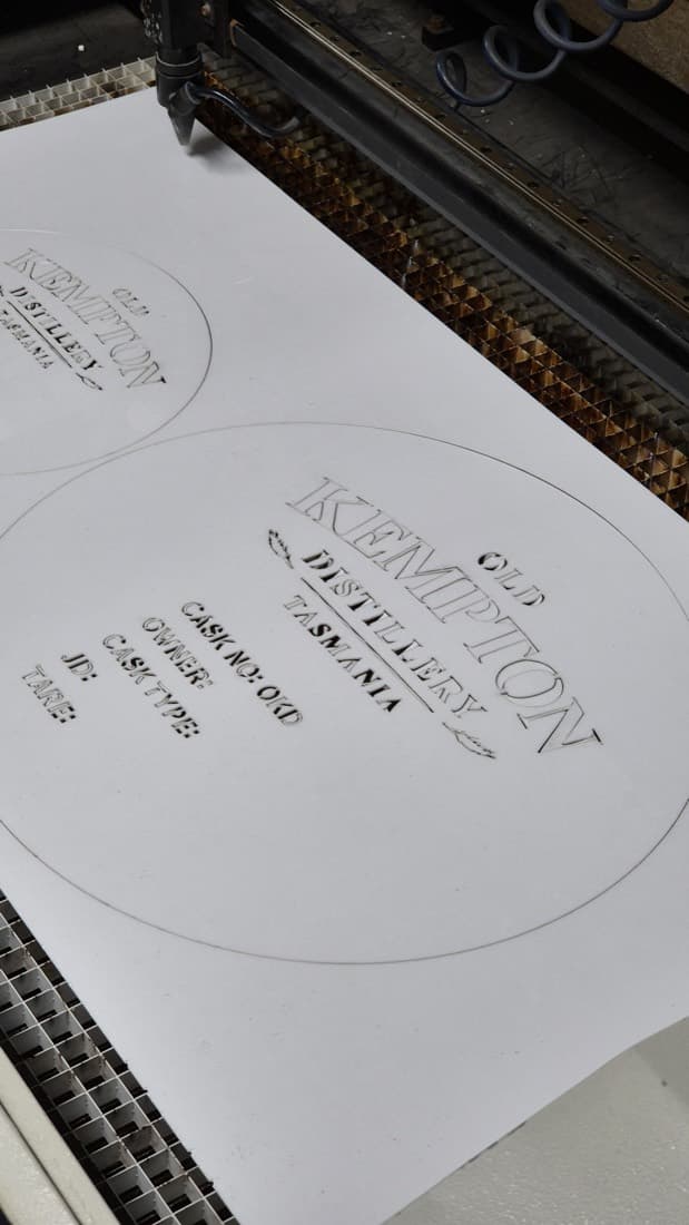Laser cutting machine engraving custom Old Kempton Distillery cask identification plates on the cutting bed